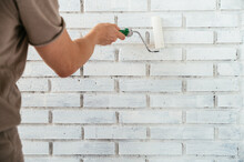 Man With Roller Painting Brick Wall