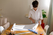 © ByLorena/Stocksy - Front view of a pre-teen Boy starting a design project and unrolling a white roll paper