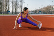 © Mihajlo Ckovric/Stocksy - Woman stretching at the athletic stadium