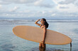 © Yury Goryanoy/Stocksy - Girl in with a surfboard looks at the ocean and waves. Surfer girl
