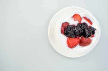 Canvas Print - Top view of yogurt with strawberries and blueberry jam isolated on light gray background