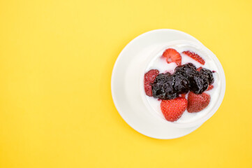 Sticker - Top view of yogurt with strawberries and blueberry jam isolated on yellow background