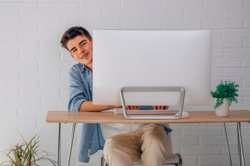 Wall Mural - satisfied male teenage student at desk with computer