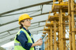 © pressmaster - Happy female engineer with tablet looking at huge construction frame