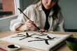 © Guaita Studio/Stocksy - Young woman writing japanese kanji characters with a brush and ink