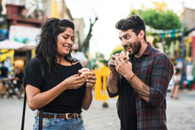 Couple eating popular street food in Caminito, a tourist spot in Buenos Aires