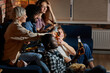 © alfa27 - Multi-ethnic group of friends having small home party, meeting, sitting on couch, clinking bottles of beer, spending, enjoying time together, watching tv at night. side view