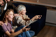 © alfa27 - Young friends having fun by playing game console at home, indoors, in the evening or at night. Friendship, leasure, rest, home party concept