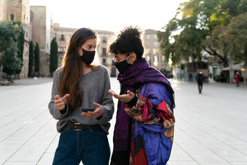 Two young woman using protective face mask during the Covid-19