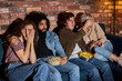 © alfa27 - Group of friends watching scary movie at home, eating popcorn, sitting on sofa together, closing eyes, two couples nervous scared in shock terrified