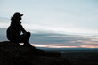 © Leah Flores/Stocksy - Silhouette of a Woman Sitting after a Hike at Sunset