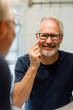 © McKinsey Jordan/Stocksy - Smiling Man Points to His Face While Looking in the Bathroom Mirror