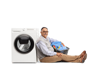 Sticker - Mature man sitting with a laundry basket and leaning on a washing machine