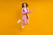 © alfa27 - Successful business woman in suit jumping pinting index finger at side, isolated on yellow background, shopping. portrait. copy space