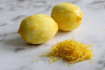 deux citrons avec la pelure grattée par un outil à zest en pile devant sur surface de marbre et lumière naturelle