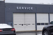 Closeup view of two overhead garage doors with the word service on the gray wall above one of the doors