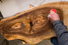 Worker's Hands Spreading Wax On Wood Board