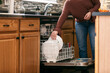 © Sean Locke/Stocksy - Home: Woman Cleaning Puts Dish In Dishwasher