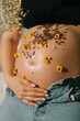 © Ani Dimi/Stocksy - Crop of pregnant woman with flowers