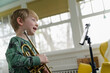 © jamie grill atlas/Stocksy - Little Boy Talking to Tablet at Virtual Trumpet Lesson