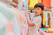 © Pansfun Images/Stocksy - Asian little girl choosing clothes in clothing store