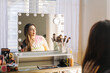© ByLorena/Stocksy - Woman with charming makeup and smile looking in mirror