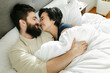 © Leah Flores/Stocksy - Smiling Couple Snuggling in Bed