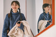 © Pansfun Images/Stocksy - Young Asian female holding mobile phone and coat in front of the