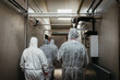 © Melissa Milis Photography/Stocksy - People wearing protective clothing walking away in a building