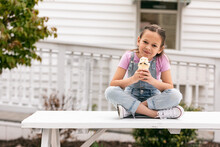 Smiling Girl Enjoys Cookie Ice Cream Cone On Picnic Table