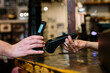 © Jimena Roquero/Stocksy - Detail shot of hand holding a smart phone doing a wireless payment at a restaurant