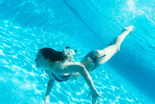 Woman Swimming Underwater In Pool