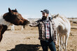 © Leah Flores/Stocksy - Man Petting Horse in Corral