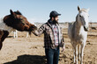 © Leah Flores/Stocksy - Cowboy in Corral with Horses