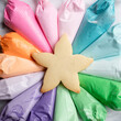 © Jennifer Bogle/Stocksy - Starfish cookie surrounded by array of rainbow frosting
