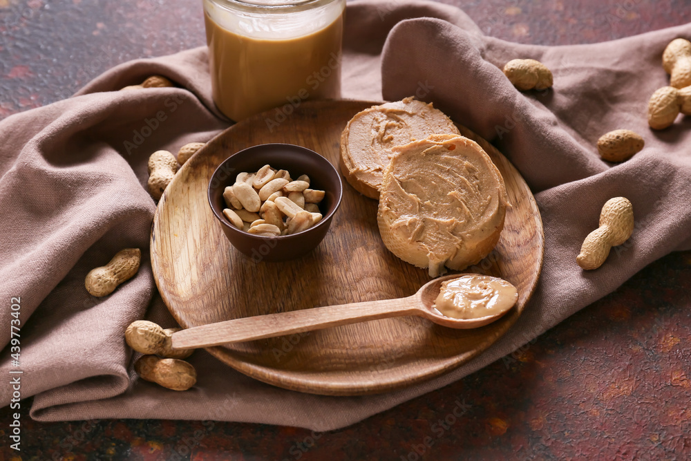 Plate with tasty peanut butter and bread on color background