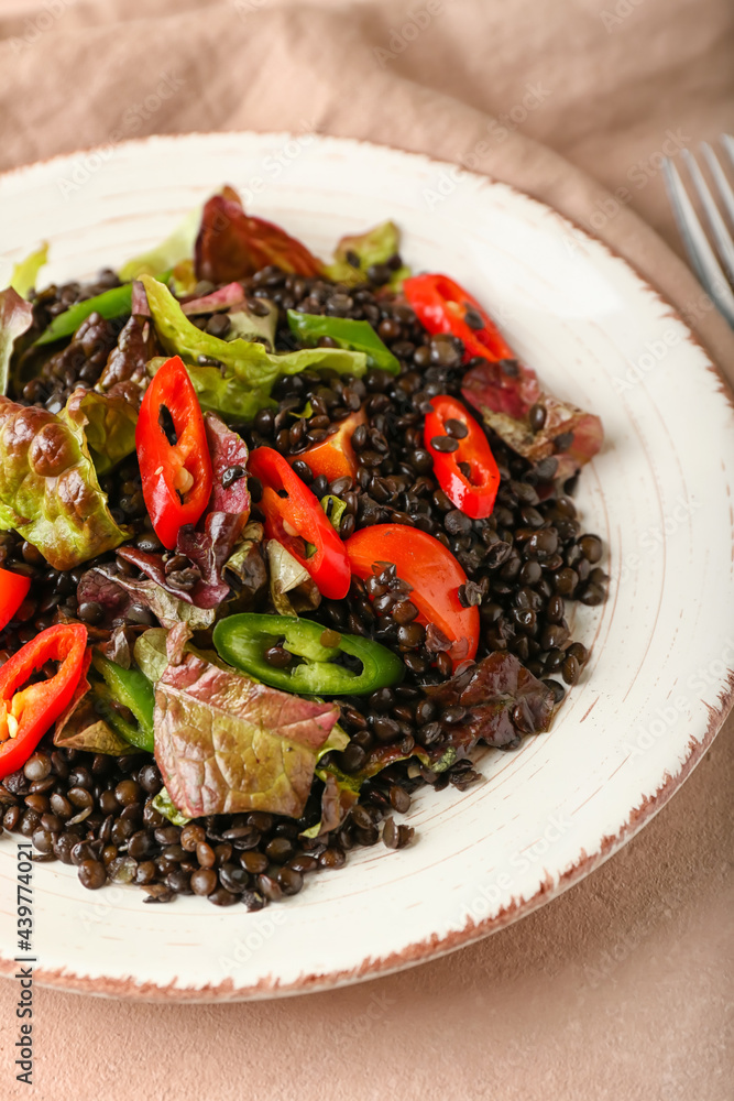 Plate with tasty cooked lentils and vegetables on color background, closeup