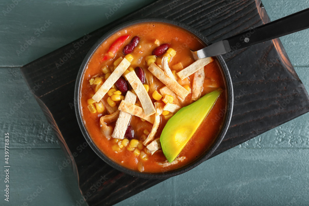 Bowl of tasty chicken enchilada soup on table