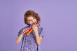 © zamuruev - Teen age Girl in blue summer flower print dress holding pop it antistress toy on lavender background, isolate.