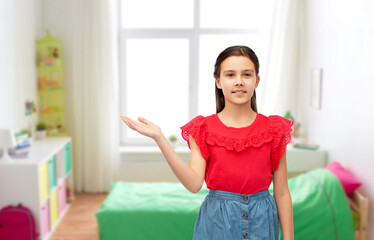 childhood, fashion and people concept - happy smiling girl holding something imaginary on her hand over white background