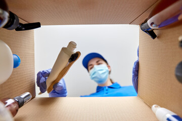 Wall Mural - home delivery, shipping and pandemic concept - woman in protective medical mask and gloves packing parcel box with cosmetics and beauty products