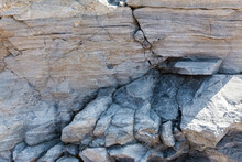 A Sheer Cliff Of Rough Sandstone. The Pattern And Texture Of Natural Stone. As A Stone Background.