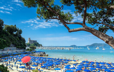 crowded beach on the Ligurian Sea, Lerici , Italy with blue umbrellas