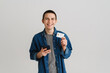 © Drobot Dean - Young white man using cellphone while posing with credit card