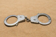 Closed handcuffs on the sand, close-up