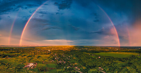 a huge double rainbow after rain over a small town among the fields. a unique atmospheric phenomenon
