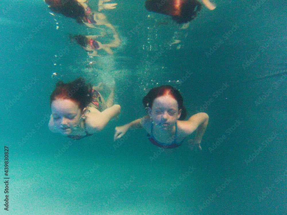Two girls swimming underwater in a pool Stock Photo | Adobe Stock