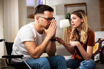 Wall Mural - Young sad man in a wheelchair. Girlfriend comforting her sad boyfriend.