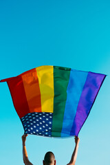 Poster - young man waving a rainbow US flag on the sky