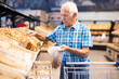 © caftor - elderly man buying bread and pastries in grocery section of the supermarket